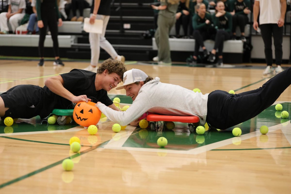 While playing "Hungry Hungry Hippos" at the fall sports assembly on Nov. 14, junior Dylan Cross and senior Fynn Carhart work to collect the balls to earn their class points.